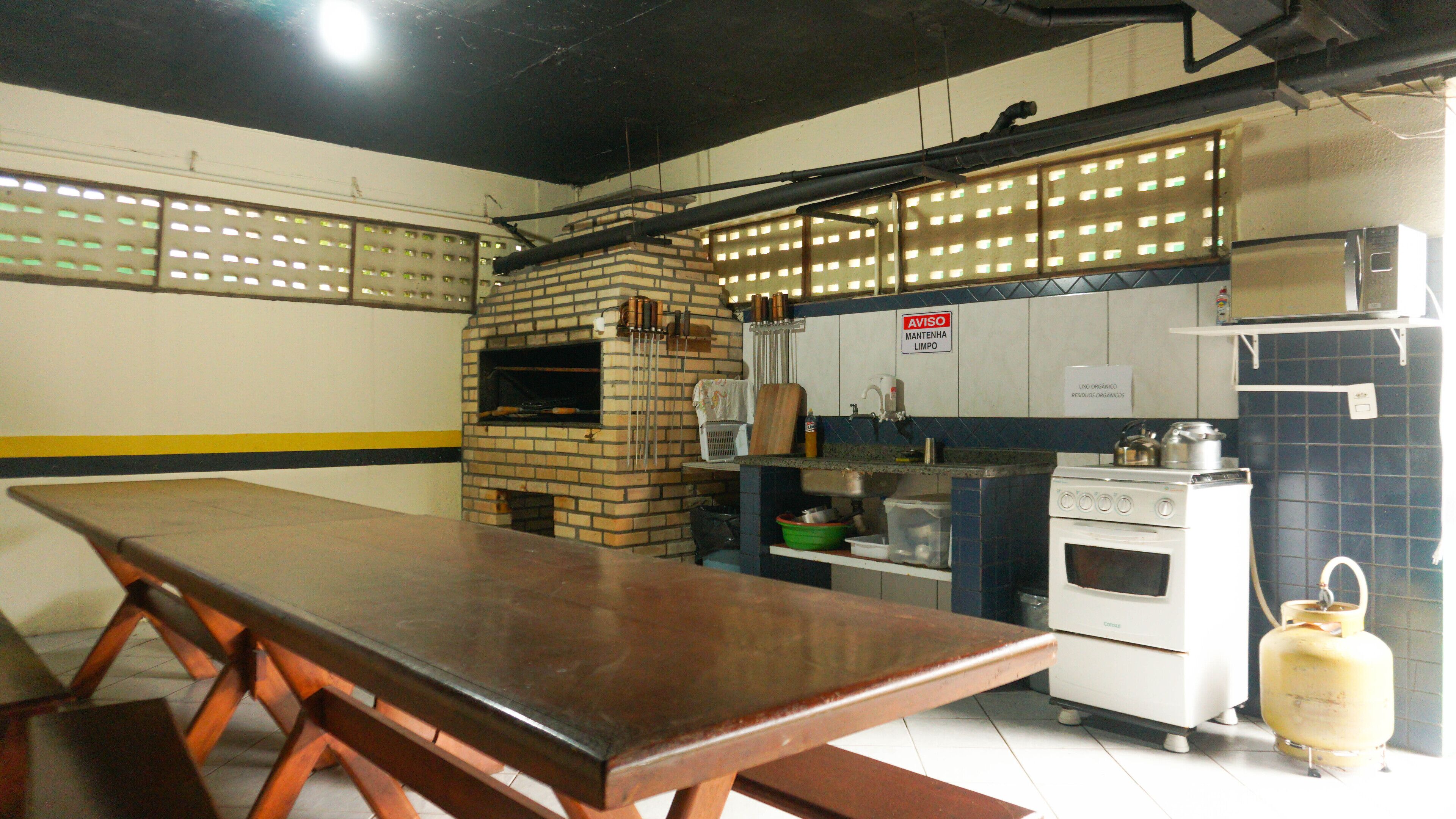 A kitchen with a brick oven, a gas stove, and a long wooden table.