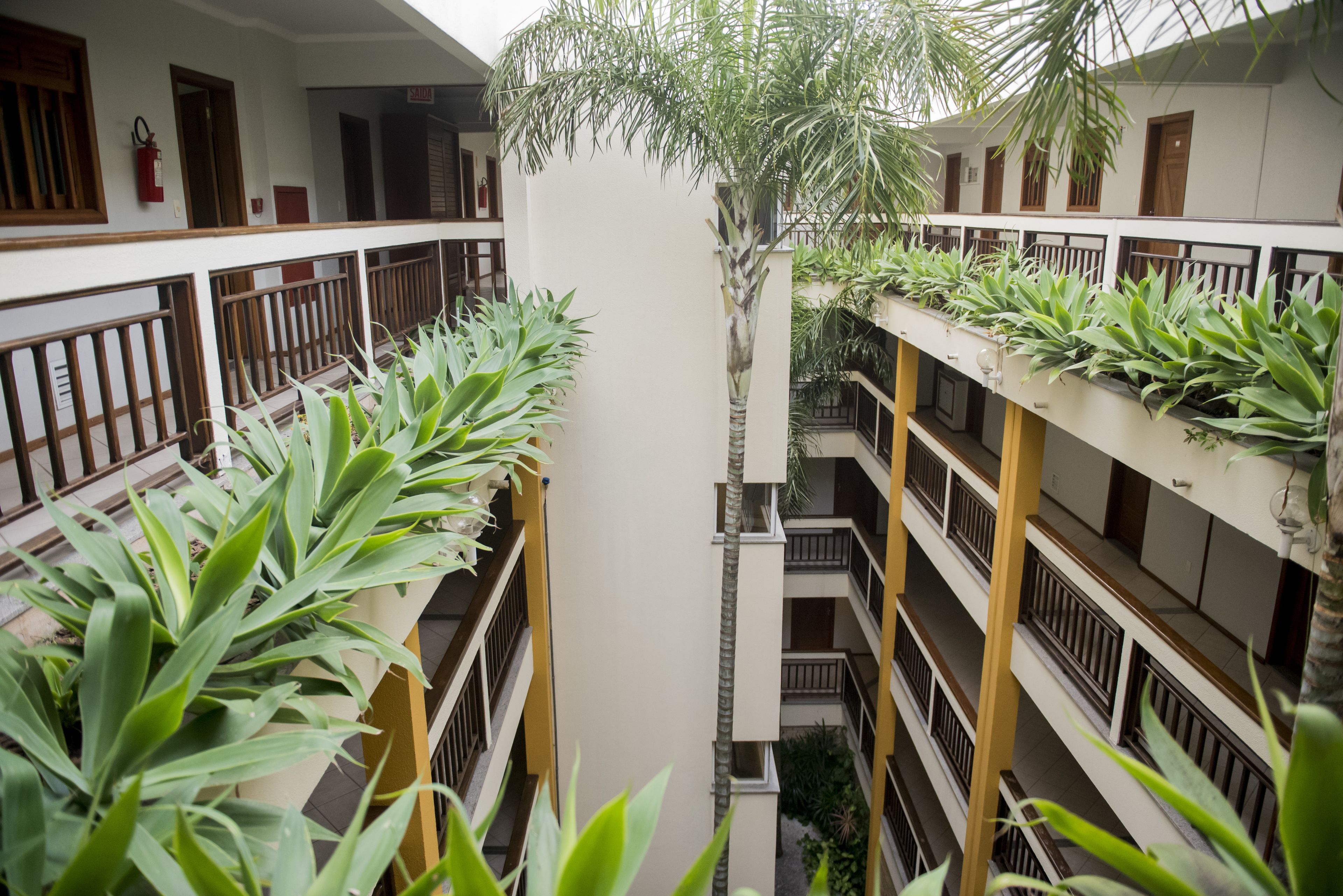 Un edificio de varios niveles con balcones, cada uno decorado con plantas en macetas.