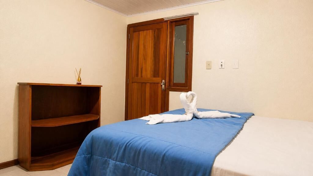 Een hotelkamer met een bed, een houten garderobe en een plankunit.