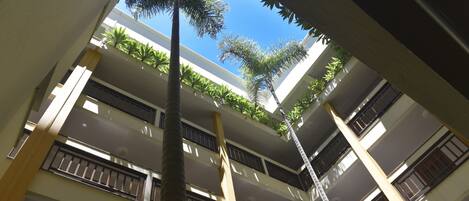 Un edificio de varios pisos con balcones y un atrio central con plantas.