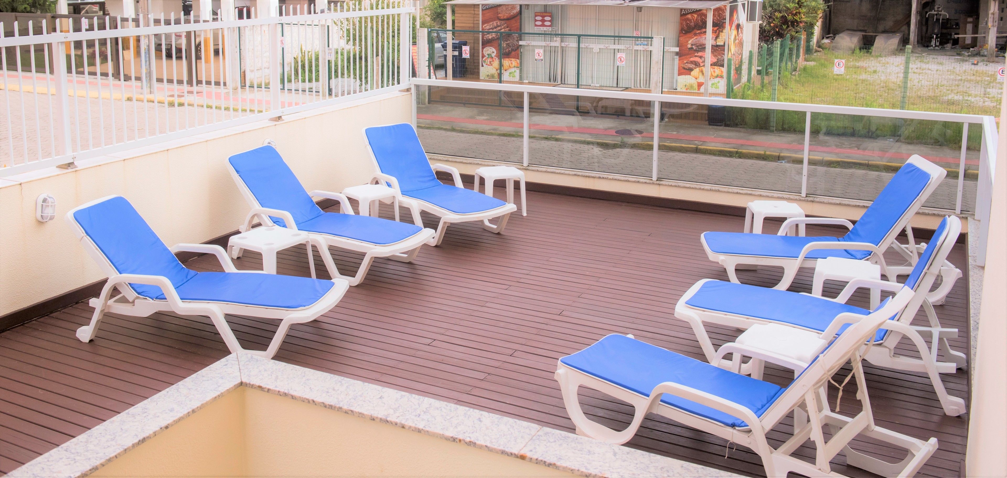 A deck with white lounge chairs and a view of the street.