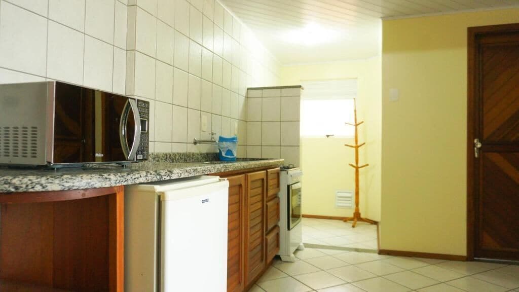 A kitchen with a refrigerator, microwave, and wooden cabinets.