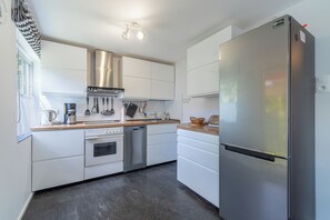 A modern kitchen with stainless steel appliances, white cabinetry, and a wooden countertop.