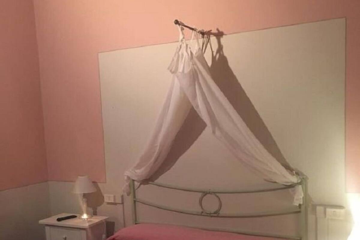 A bedroom with a bed, a nightstand, a lamp, and a canopy bed.