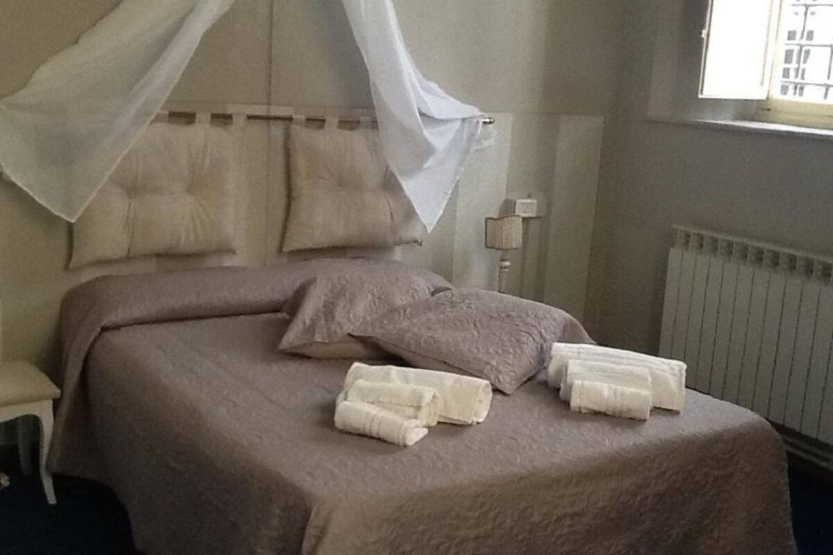 A neatly made bed with a canopy, pillows, and towels.
