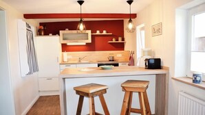 A kitchen with a wooden island, two stools, a microwave, and a coffee machine. - Haus Hanna (Dagebuell)