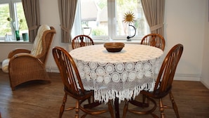 A round dining table with a crocheted tablecloth, surrounded by wooden chairs. - Haus Hanna (Dagebuell)