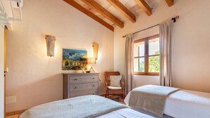 Un dormitorio con dos camas, un aparador, una silla, un cuadro y una ventana con cortinas.