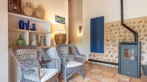 Una habitación con sillas de mimbre, una lámpara y una pared de piedra.