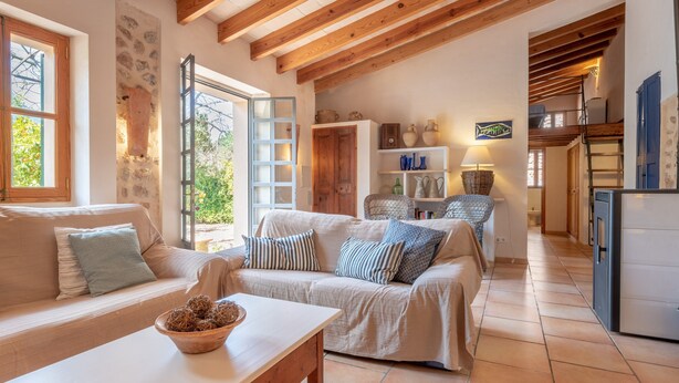 Una sala de estar acogedora con un sofá, una mesita de centro y una zona de cocina con refrigerador y estanterías.