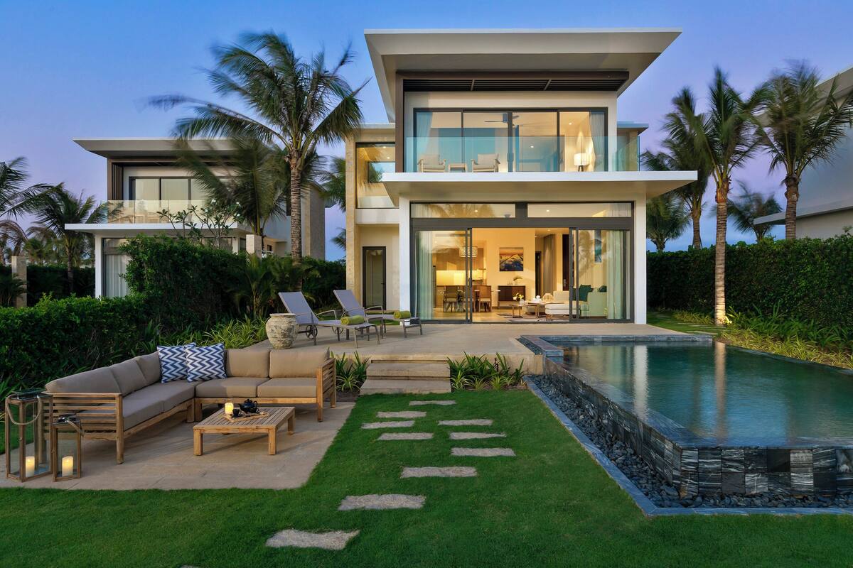 Een modern huis met twee verdiepingen, een zwembad, terras en een verzorgde tuin.