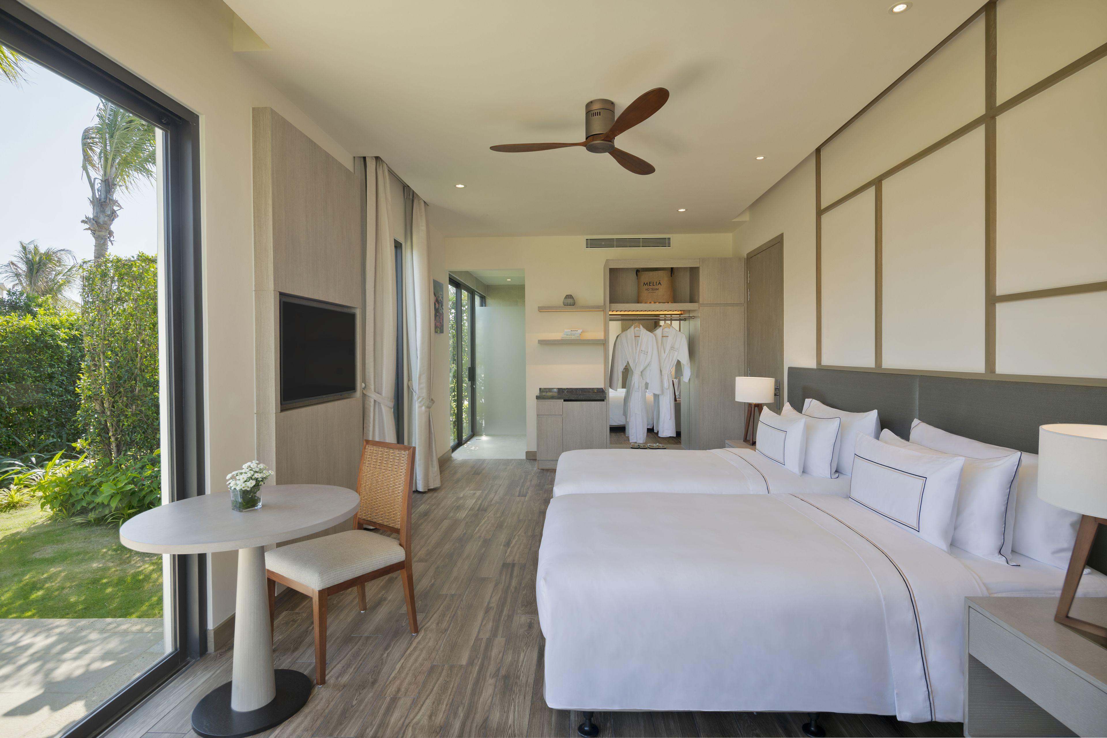 Una habitación de hotel moderna con una cama grande, una mesita y vistas al exterior.