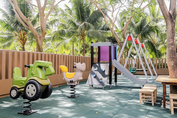 Un área de juegos infantiles con columpios, un tobogán y un coche de juguete.