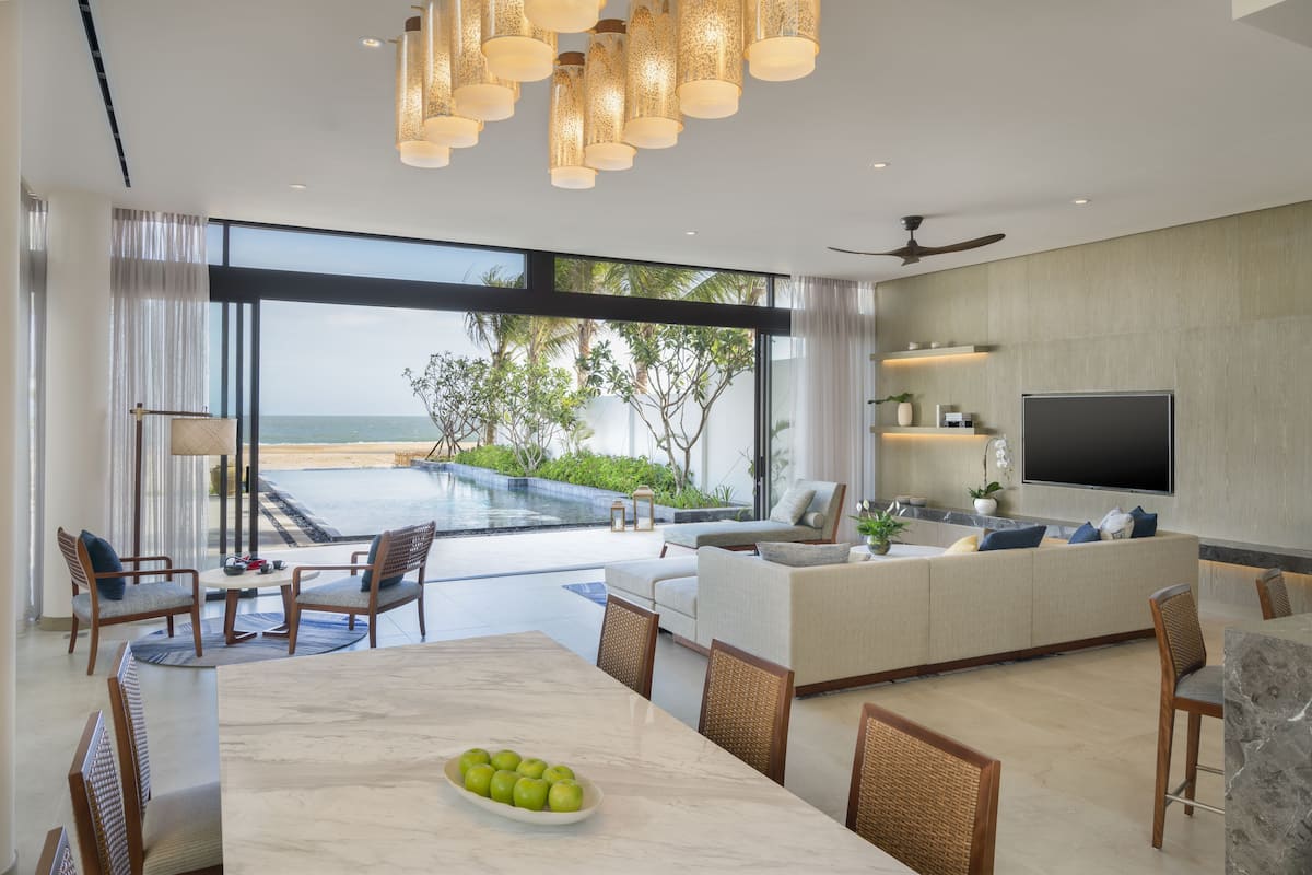 Een moderne woonkamer met een grote televisie, comfortabele zitplaatsen en uitzicht op de oceaan.