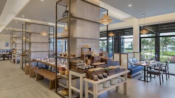 A spacious cafe with wooden furniture, a variety of baked goods, and hanging pendant lights.