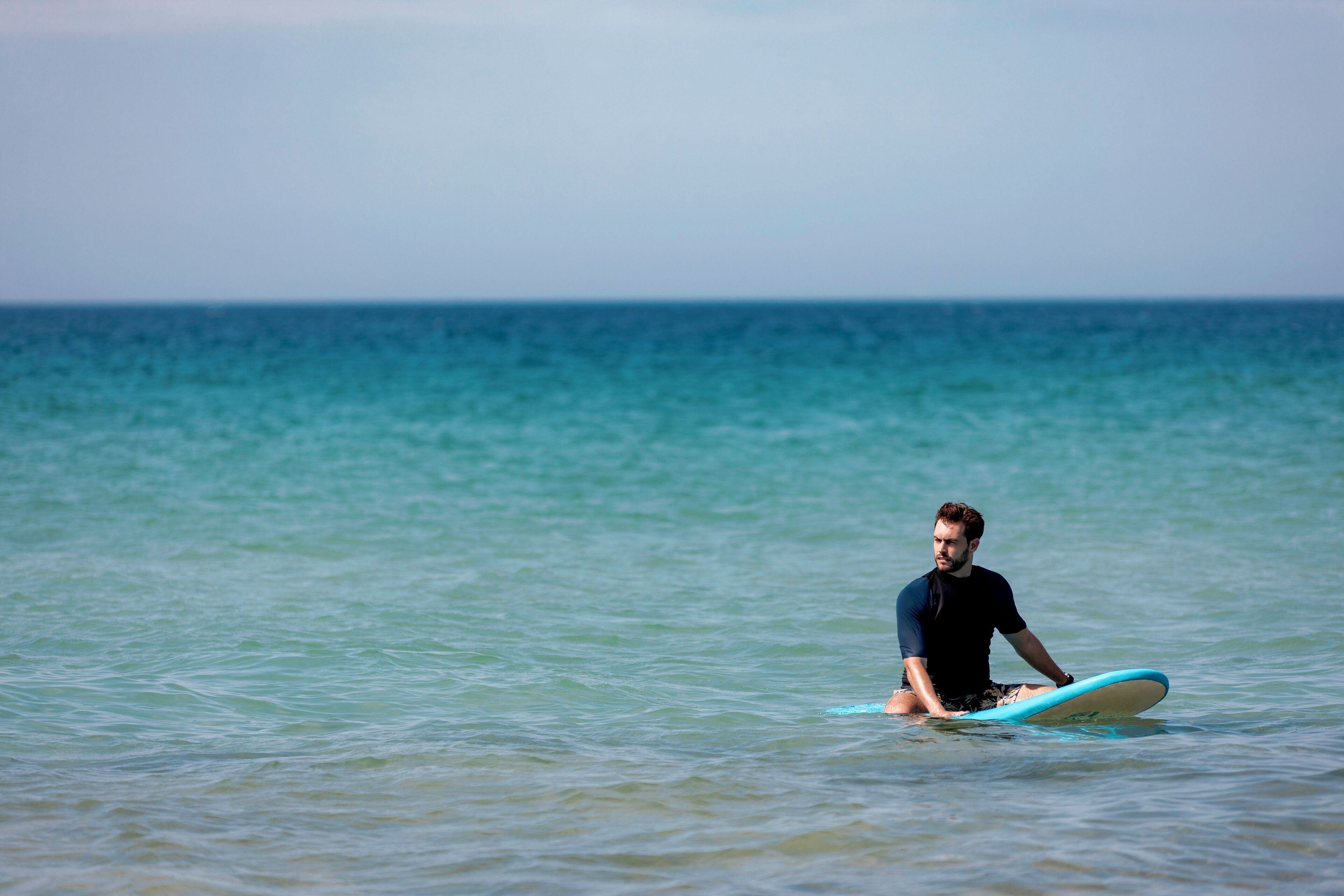 Una persona seduta su una tavola da surf nell'oceano.