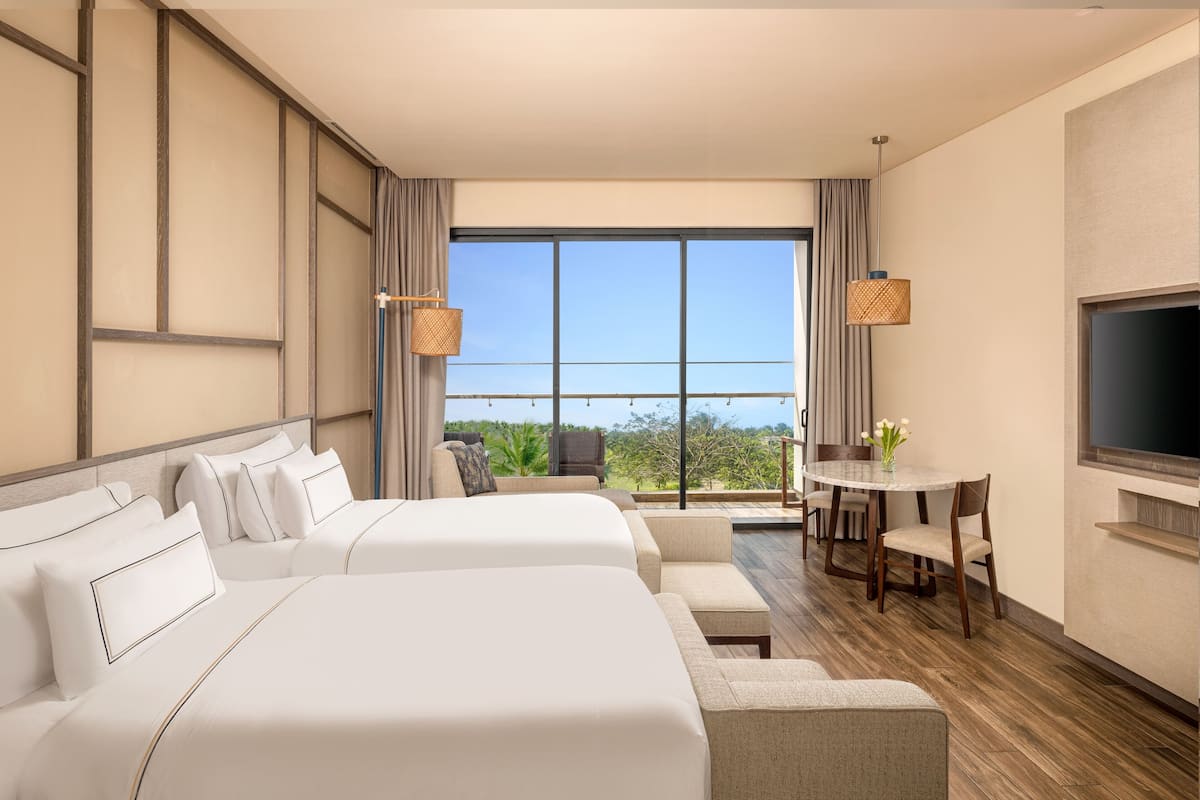 Een hotelkamer met twee bedden, een eethoek en een televisie.