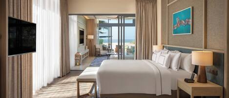 Habitación de hotel con cama, mesita de noche, televisión y vista al mar.