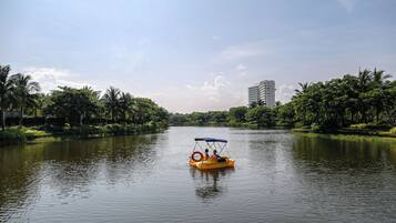 A river with a yellow boat, surrounded by greenery and a tall building in the background.