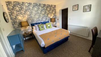A bedroom with a large bed, two bedside lamps, a radiator, and a blue cabinet.