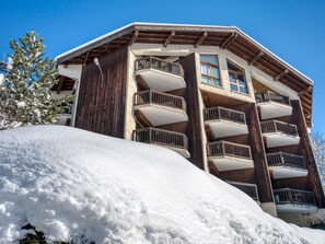 Un edificio de varios pisos con balcones, rodeado de nieve.