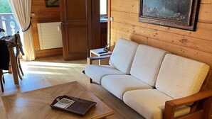A cozy room with a wooden floor, a beige sofa, a wooden coffee table, and a framed picture on the wall.