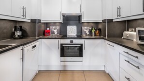 Eine moderne Küche mit weißen Schränken, einem Bosch-Ofen, einer Kaffeemaschine und einem Toaster.