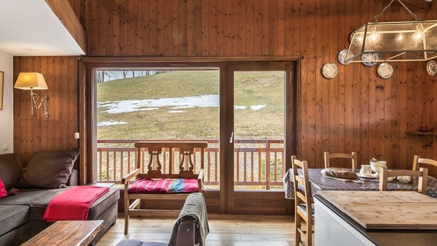 L’intérieur d’un chalet accueillant, avec une terrasse en bois, un canapé, un banc et un coin repas comprenant une table et des chaises.