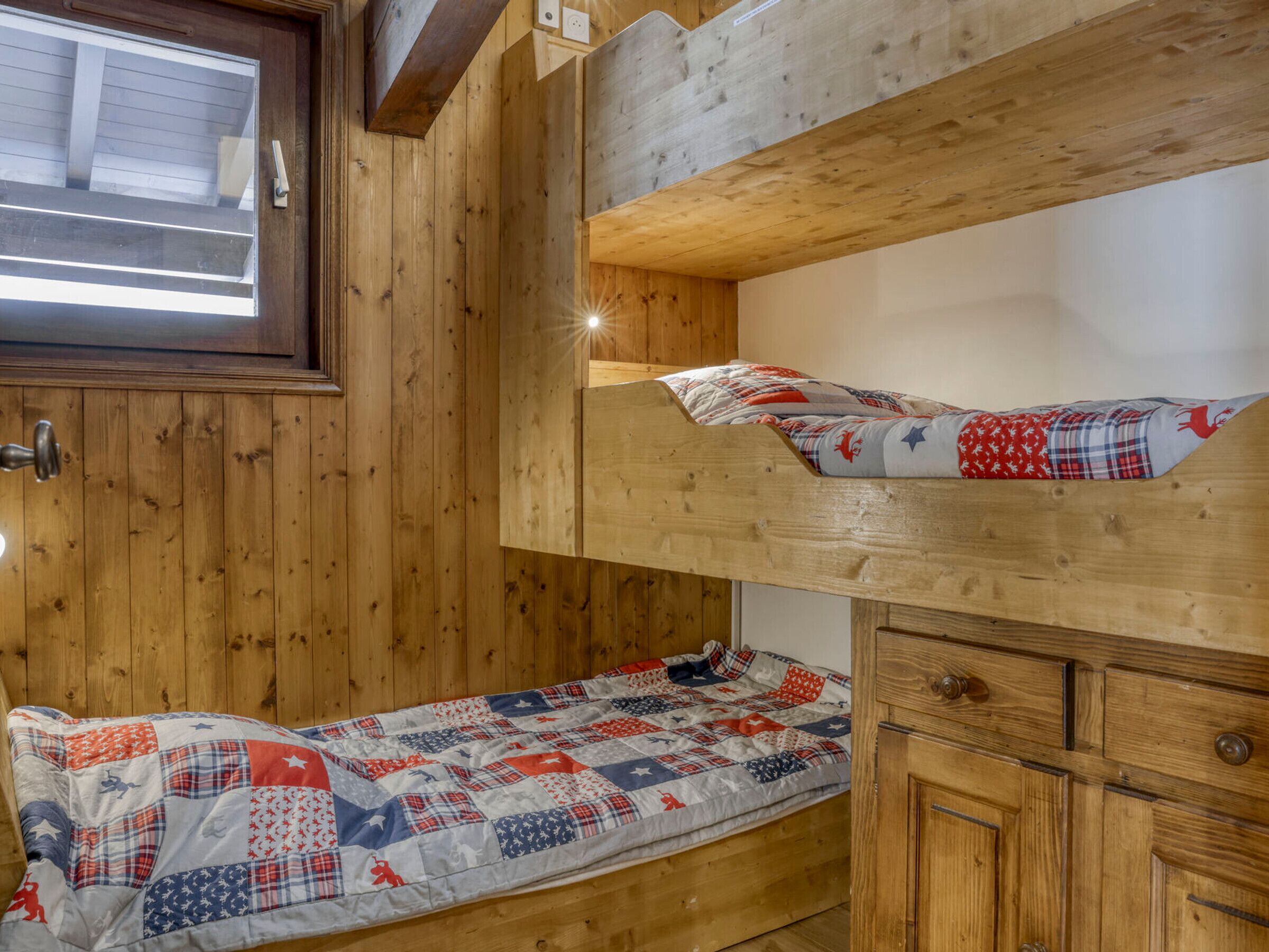 A wooden cabin with bunk beds and a small cabinet.