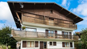 A two-story building with a stone base and wooden upper levels, featuring balconies and large windows.