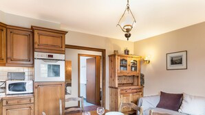 A cozy kitchen with wooden cabinets, a microwave, and a dining table set for four with wine glasses and plates.