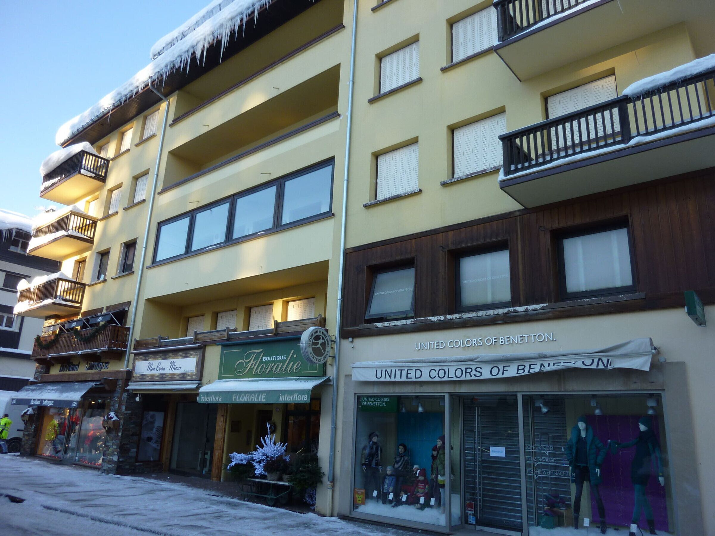 Un edificio de varios pisos con diversas tiendas, incluyendo una floristería y una boutique.