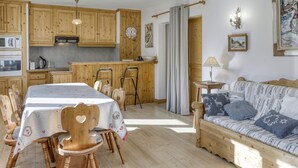 Een gezellige keuken met houten kasten, een eettafel met stoelen, een bank en een klein bijzettafeltje met een lamp.
