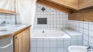 A bathroom with a wooden ceiling, a bathtub, a sink, and a mirror.