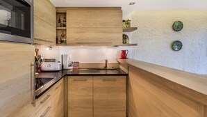 Una cucina compatta con mobili in legno, forno integrato e macchina per il caffè.