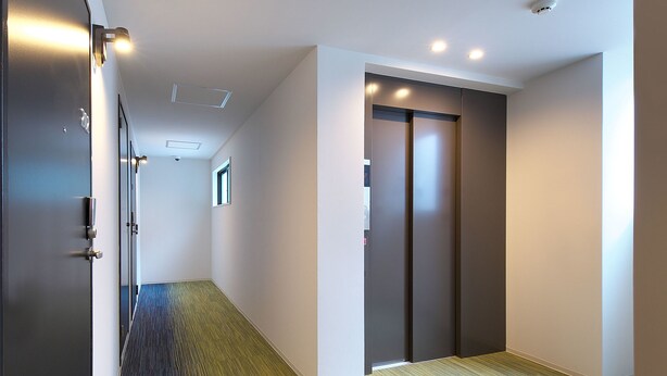 A hallway with a carpeted floor, a door on the left, and a door on the right. - e-stay ebisu (Osaka)