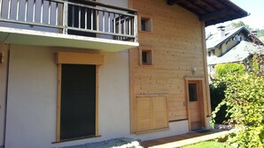 A two-story wooden building with a balcony, a door, and a small window.