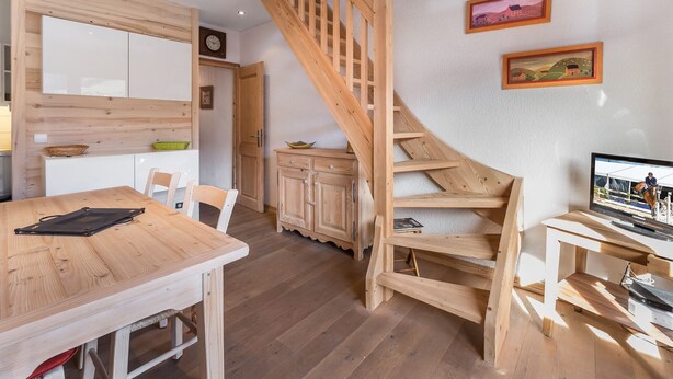 Un interior moderno con una escalera de madera, un comedor y un televisor.