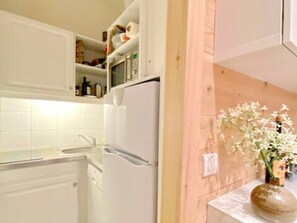 Eine Küche mit weißen Schränken, einem Kühlschrank und einer Holzwand.