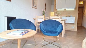 Una cocina moderna con armarios de madera y un comedor con dos sillas azules y una mesa redonda.