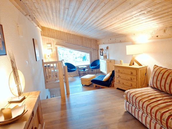 Un intérieur en bois comprenant un canapé, une commode, une chaise et une lampe.