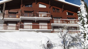 Un edificio de madera de varios pisos con balcones, rodeado de nieve.