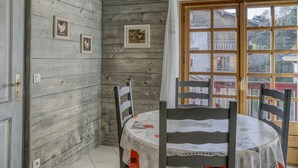 A rustic dining area with wooden walls, a round table, and chairs. - 2-Bedroom Apartment in Megève Center with WiFi (Megève)