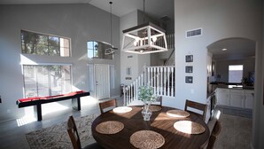 Uma área de jantar espaçosa com uma mesa redonda de madeira, jogos americanos trançados e um banco ao fundo.