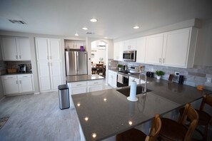 A modern kitchen with white cabinets, stainless steel appliances, and a central island.