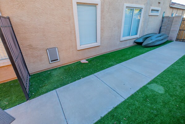 A residential area with a well-maintained lawn, a concrete pathway, and a metal gate.
