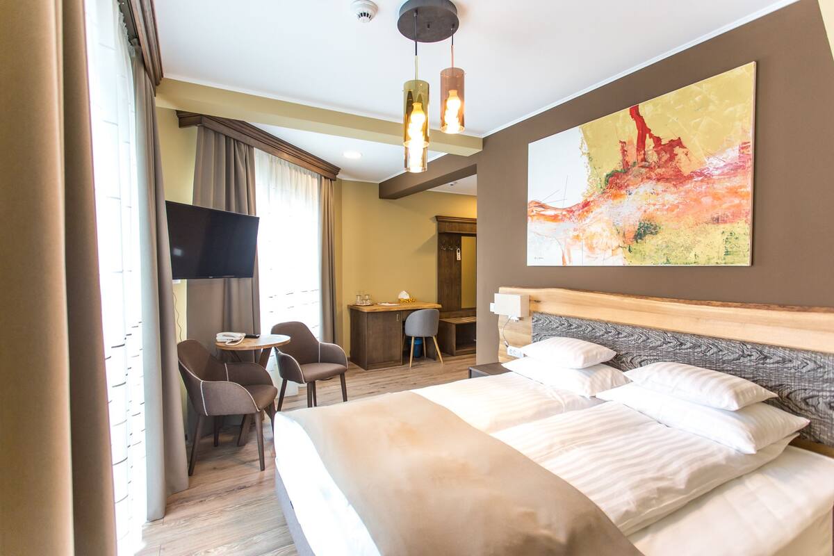 Een hotelkamer met een bed, een bureau, een stoel, een televisie en een schilderij aan de muur.
