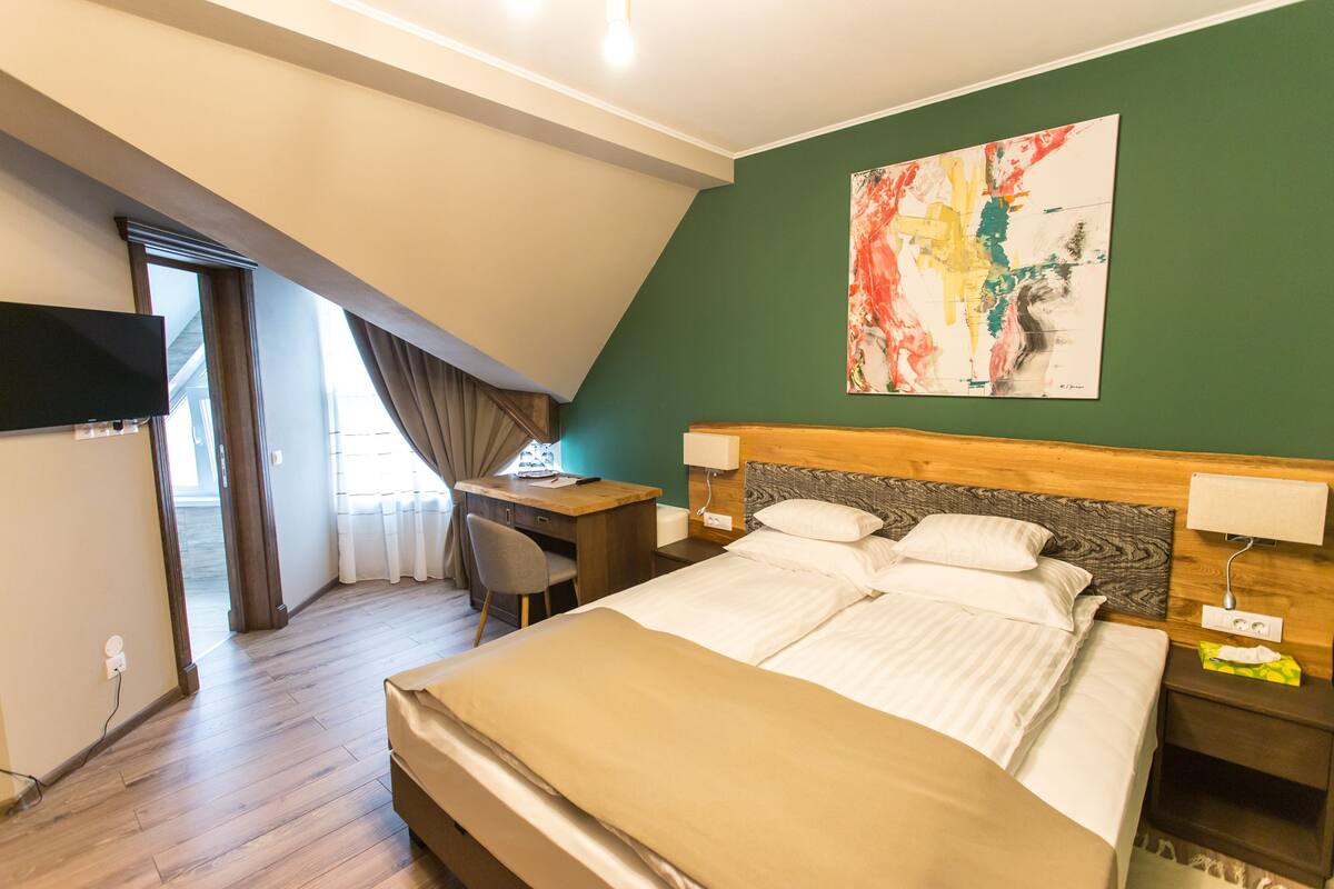Een hotelkamer met een bed, bureau, stoel en een schilderij aan de muur.