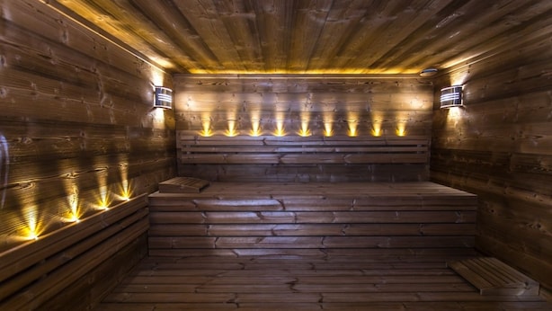 Uma sauna de madeira com bancos e luzes fixadas na parede.