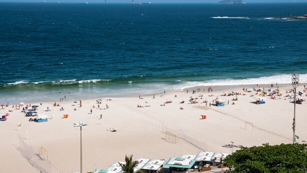 Ein Strand mit Menschen, Sonnenschirmen und Booten.